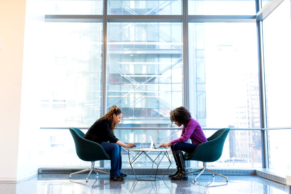 Two Woman Sitting Near Green Padded Chair