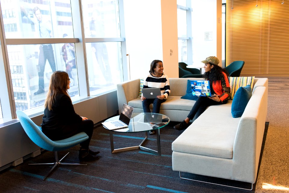 Women Sitting On Sofa Holding Laptops
