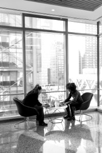 Grayscale Portrait Of Two People Sitting On Chairs photo