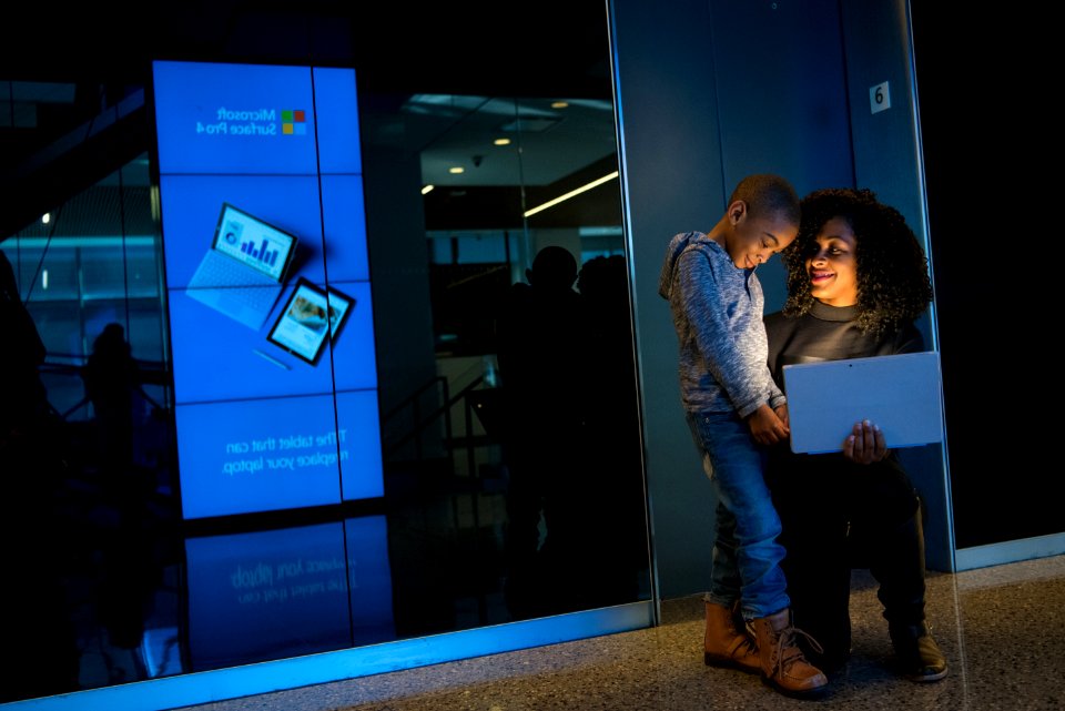 Boy In Gray Hoodie Standing Beside Woman Holding Laptop photo