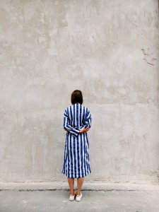 Woman Wearing Blue And White Striped Shirt Dress Facing Gray Wall photo