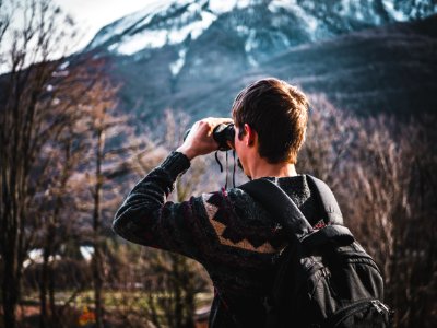 Man Using Black Binoculars Near Forest Trees At Daytime
