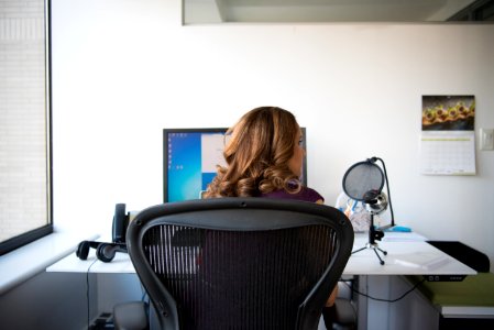 Woman Siting On Chair In Front Of Turn On Computer Monitor photo