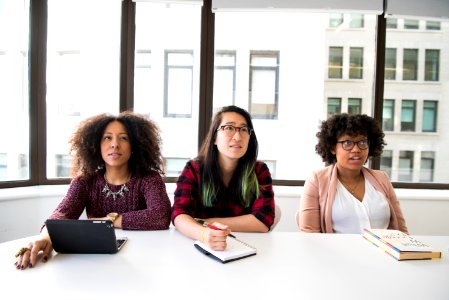 Closeup Photo Of Three Women Sit On Chair In Front Of Tables photo