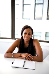 Woman Wearing Gray Tank Top And Sitting In Front Of White Table With Spiral Notebook photo