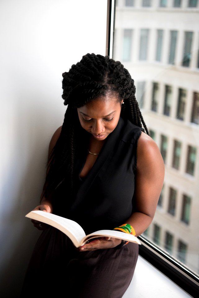 Woman Reading Book Leaning Near Wall