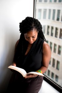 Woman Reading Book Leaning Near Wall