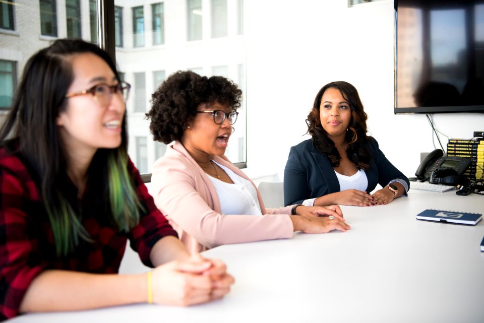 Three Women Sitting Beside White Table