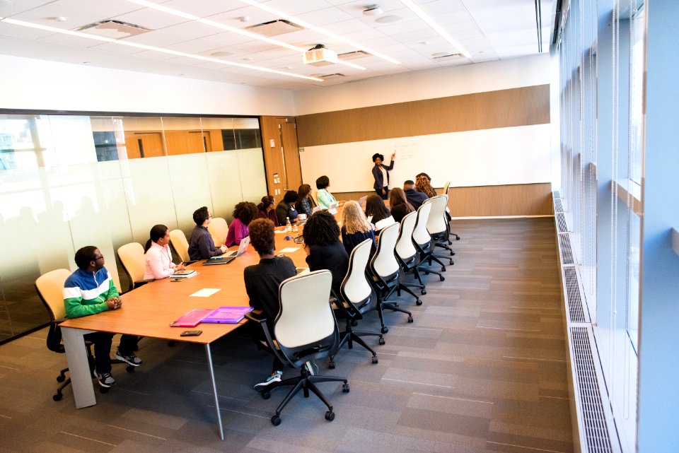 People Sitting On Beige Rolling Chairs On Brown Wooden Table Inside Room photo