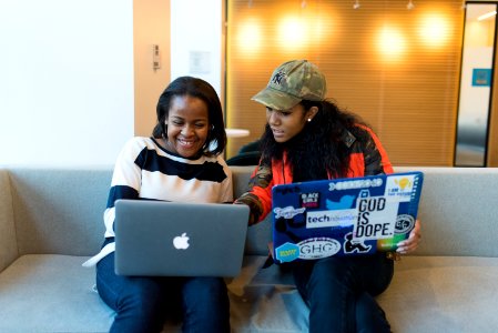 Two Woman Sitting On Sofa While Using Laptops photo