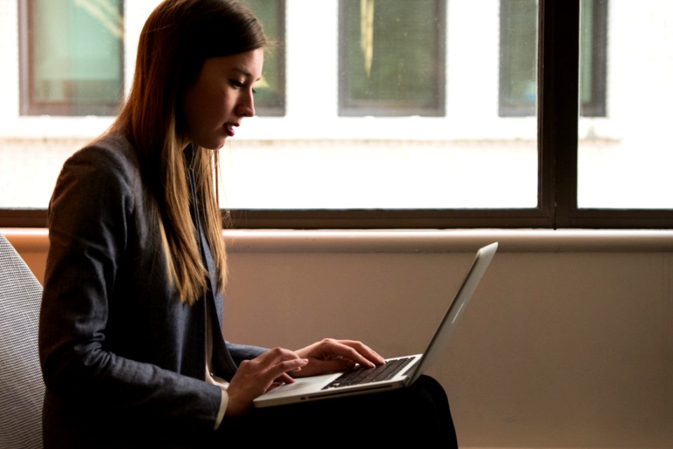 Woman Sitting Down And Using Laptop On Her Lap