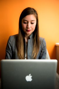 Woman In Gray Suit Coat Using Silver Apple Macbook