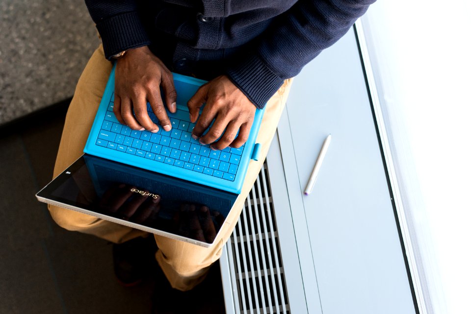 Person Typing On Blue Laptop Computer
