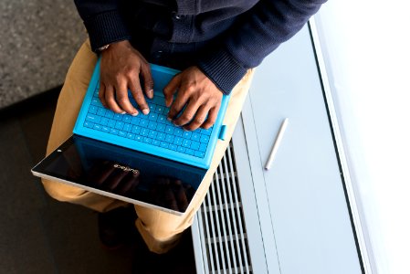Person Typing On Blue Laptop Computer