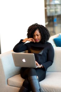 Woman In Black Outfit With MacBook Sitting On A Couch photo