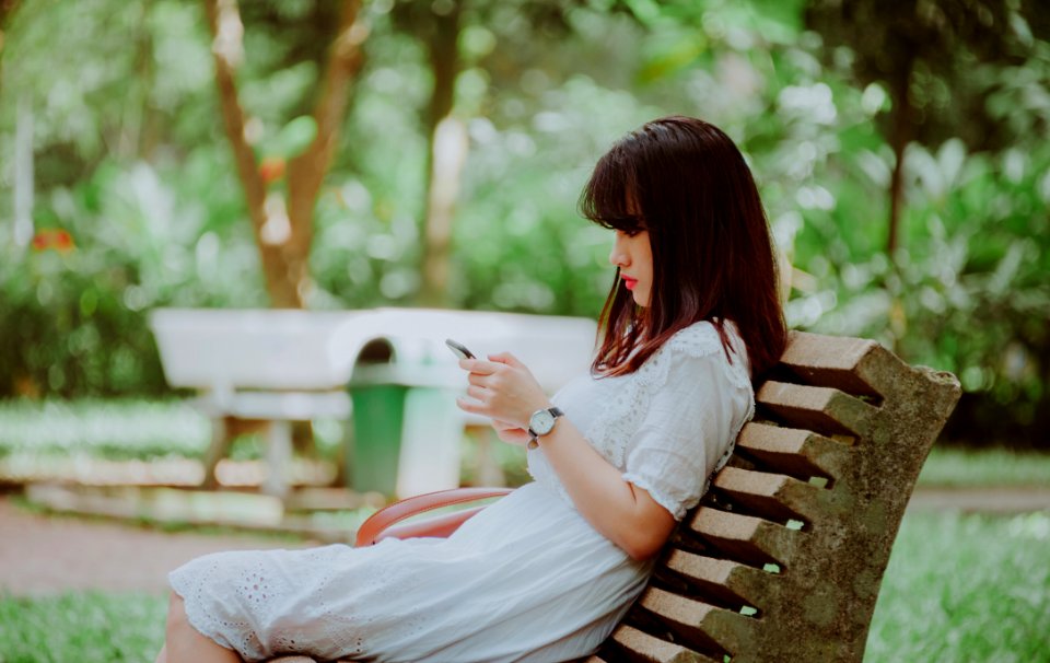 Woman Sitting On Bench Checking Her Phone