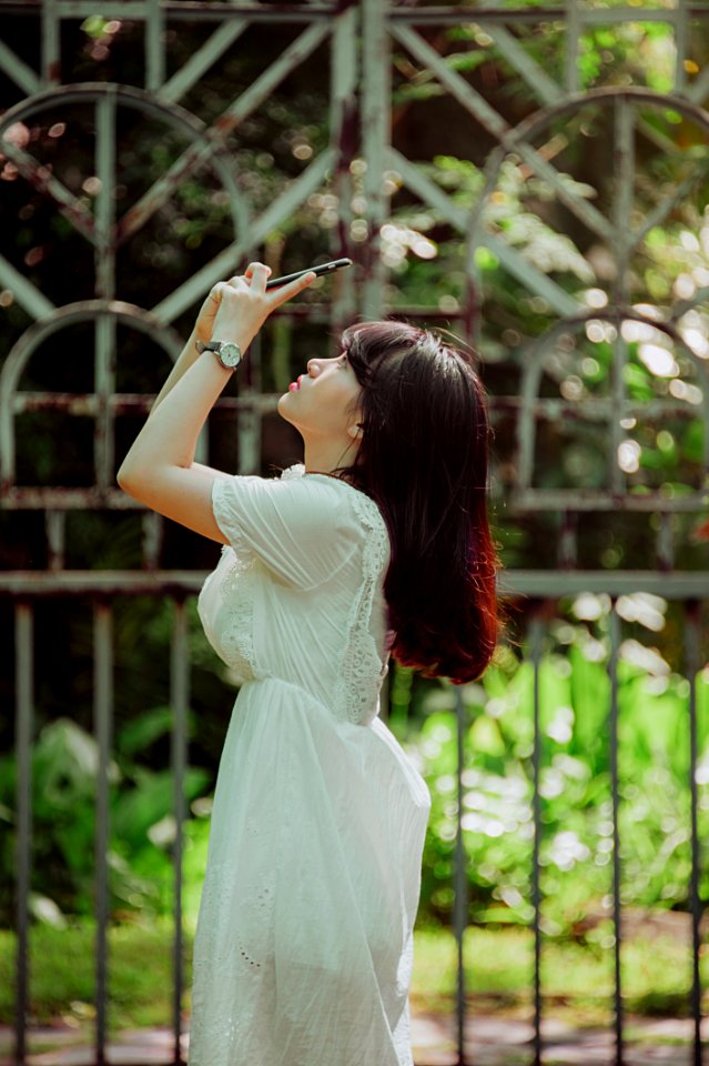 Woman Wearing White Lace Dress Staring In Her Smartphone