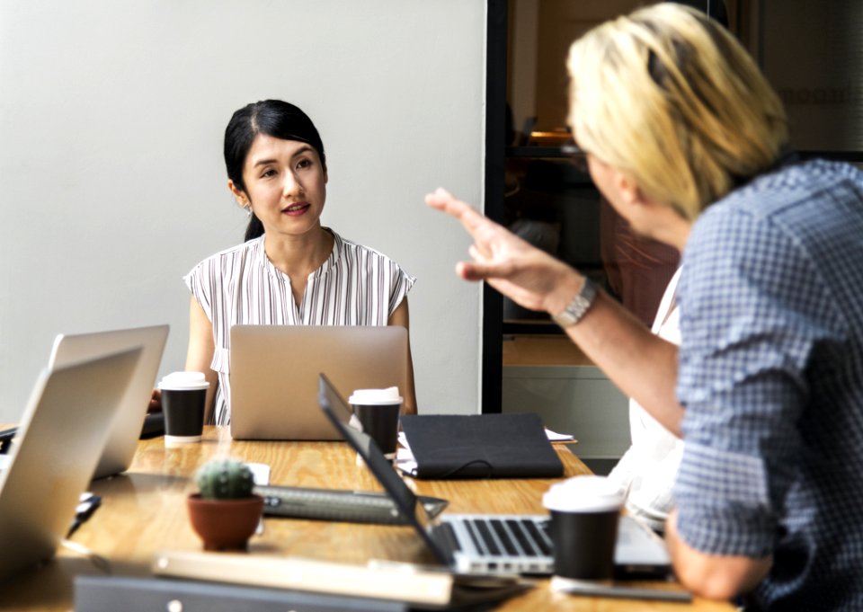 Men Talking To A Woman Sitting In Front Of Silver Laptop Computer