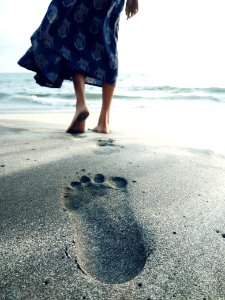 Photo Of Woman Walking Barefoot On Seashore photo