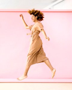 Woman Wearing Brown Dress Jump Near Pink Wall photo