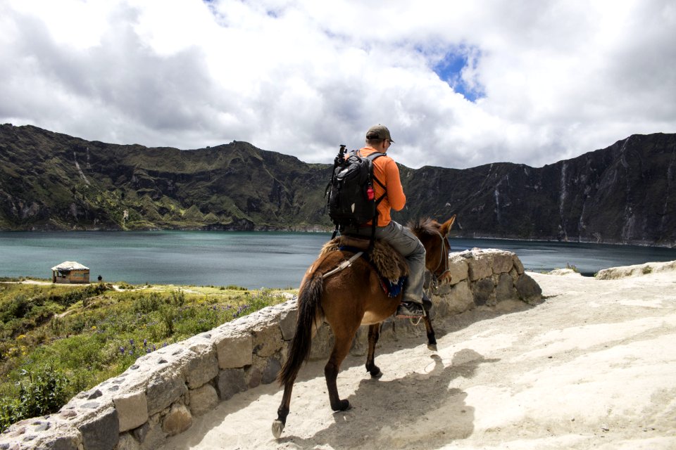 Man Carrying A Bag Pack Riding A Brown Horse