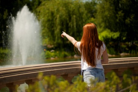 Shallow Focus Photo Of Woman Standing In Front Of Body Of Water With Fountain photo