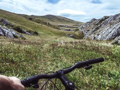 Person Riding Bicycle Overlooking Green Grass Field And Hill photo