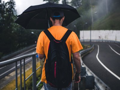 Man Wearing Orange Shirt Holding Black Umbrella