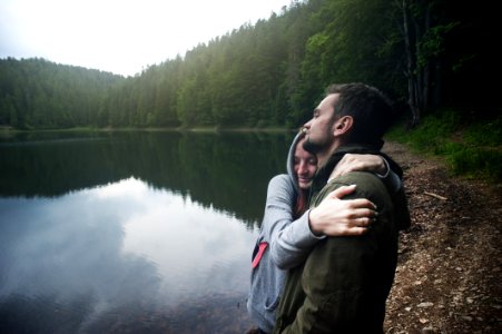 Woman Hugging Man Standing Beside Body Of Water photo