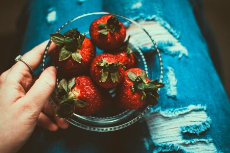 Person Holding Clear Glass Bowl Of Strawberries photo