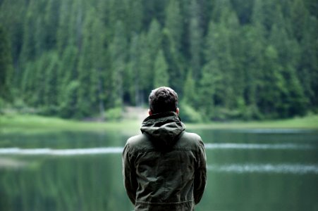 Photo Of Man Wearing Hooded Jacket In Front Of Body Of Water photo