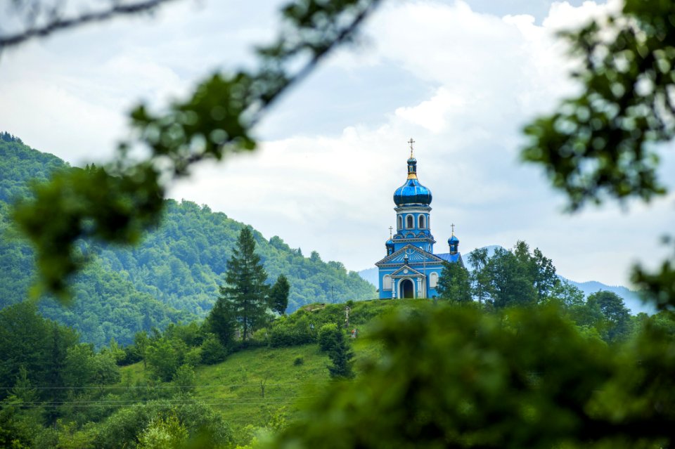 Blue Dome Building Surrounded By Tall Trees Taken Under White Clouds