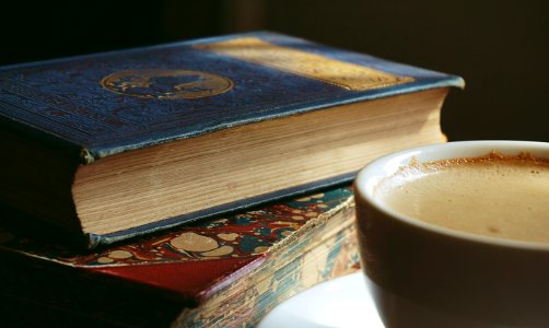 Book Beside Cup Filled With Brown Liquid photo