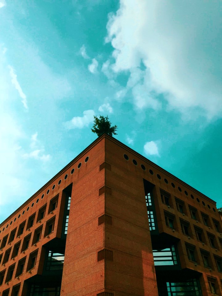 Brown Concrete Building Under Teal And White Cloudy Sky At Daytime photo