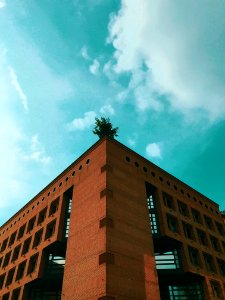 Brown Concrete Building Under Teal And White Cloudy Sky At Daytime