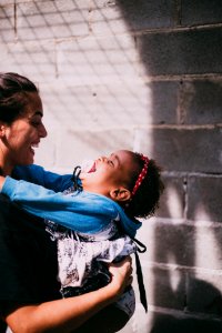 Woman In Black Top Carrying Girl Wearing Blue Hoodie photo