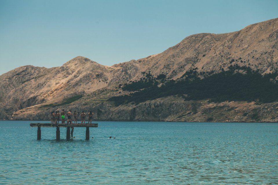 People Standing On Terrace In Middle Of Body Of Water Within Mountain Range