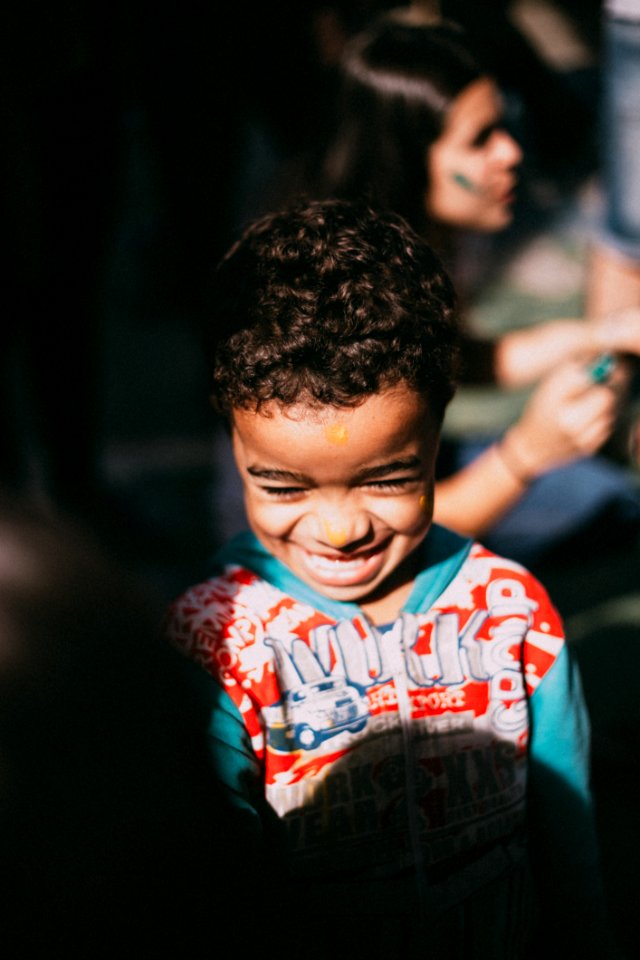 Selective Focus Photography Of A Boy Who Were Smiling In With Red And Blue Hooded Jacket photo