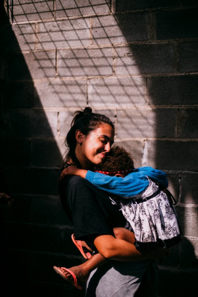 Woman Holding Girl Beside Gray Wall