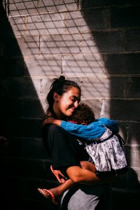 Woman Holding Girl Beside Gray Wall photo