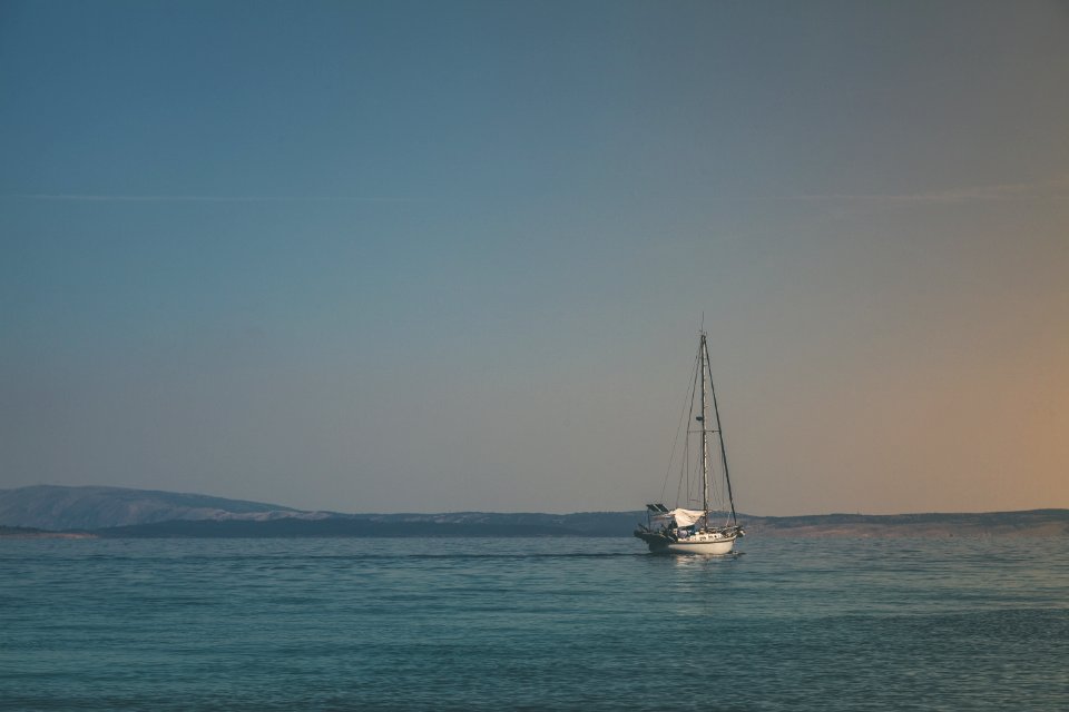 White Sailboat On Body Of Water Under White Sky