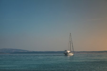 White Sailboat On Body Of Water Under White Sky photo