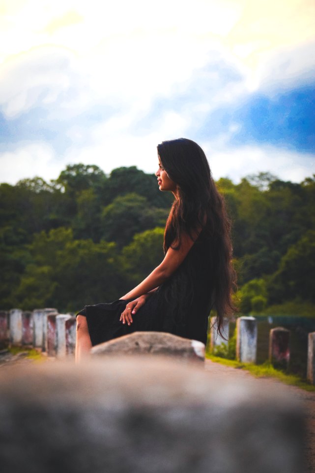 Woman Sitting On Concrete Pillar