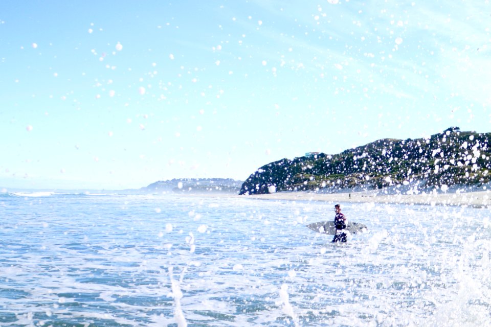 Person Carrying Surfboard Walking On Sea Water