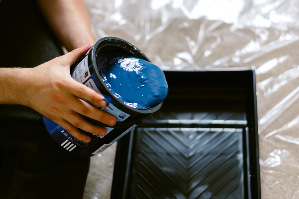 Person Holding Can Of Blue Paint