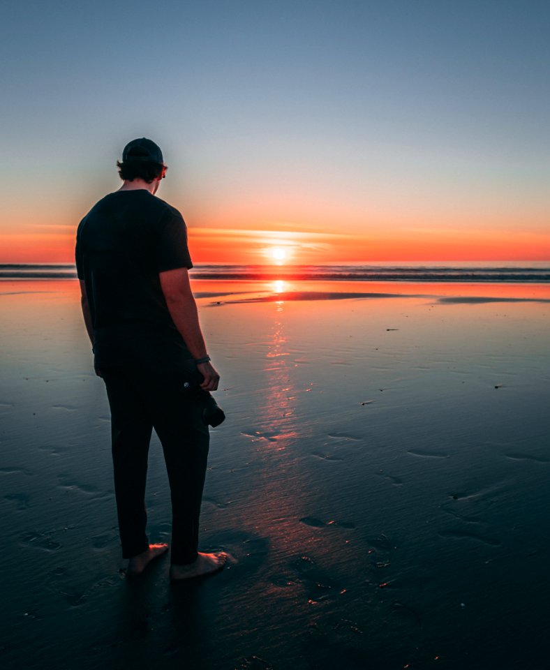 Man Standing On Beach During Sunset