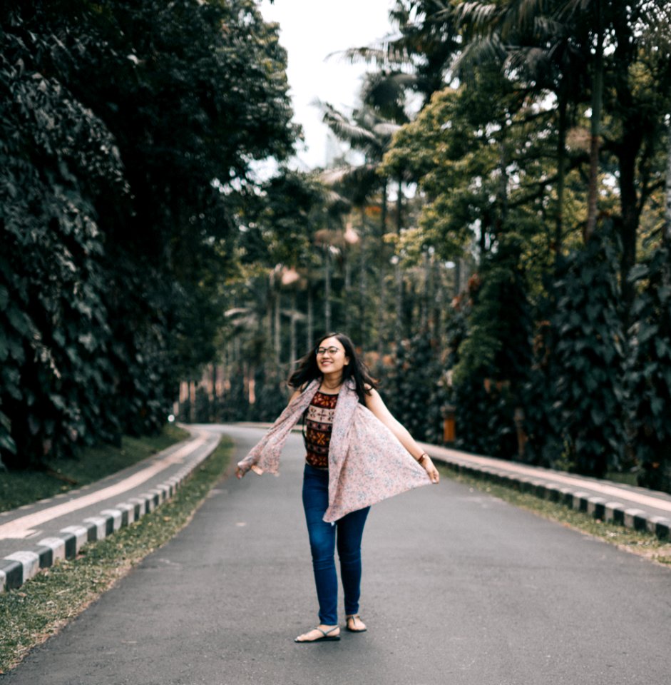 Woman Standing On Road Between Trees