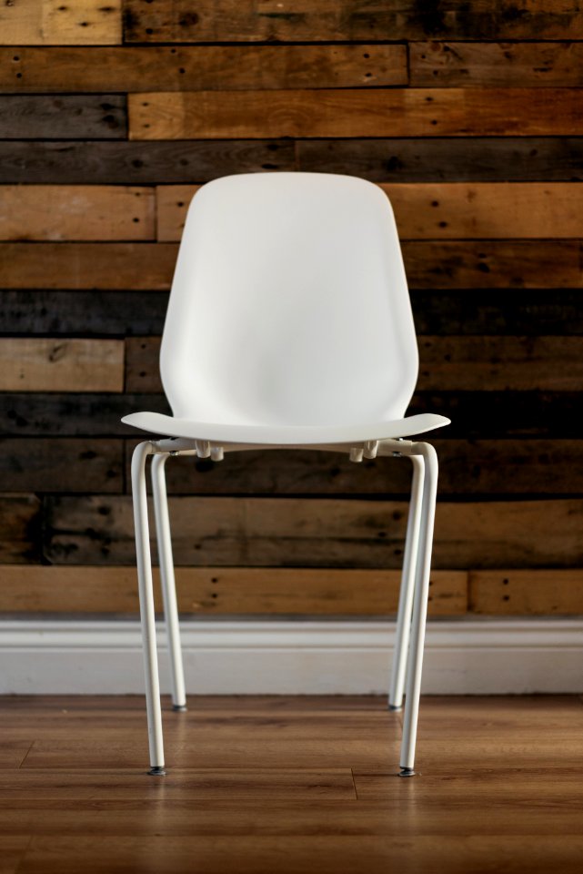 White Plastic Chair Beside Brown Wooden Wall In Home