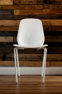 White Plastic Chair Beside Brown Wooden Wall In Home