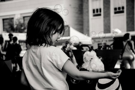 Monochrome Photography Of Girl Playing With Bubbles photo